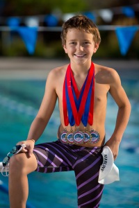 Individual portrait of boy swimmer with medals